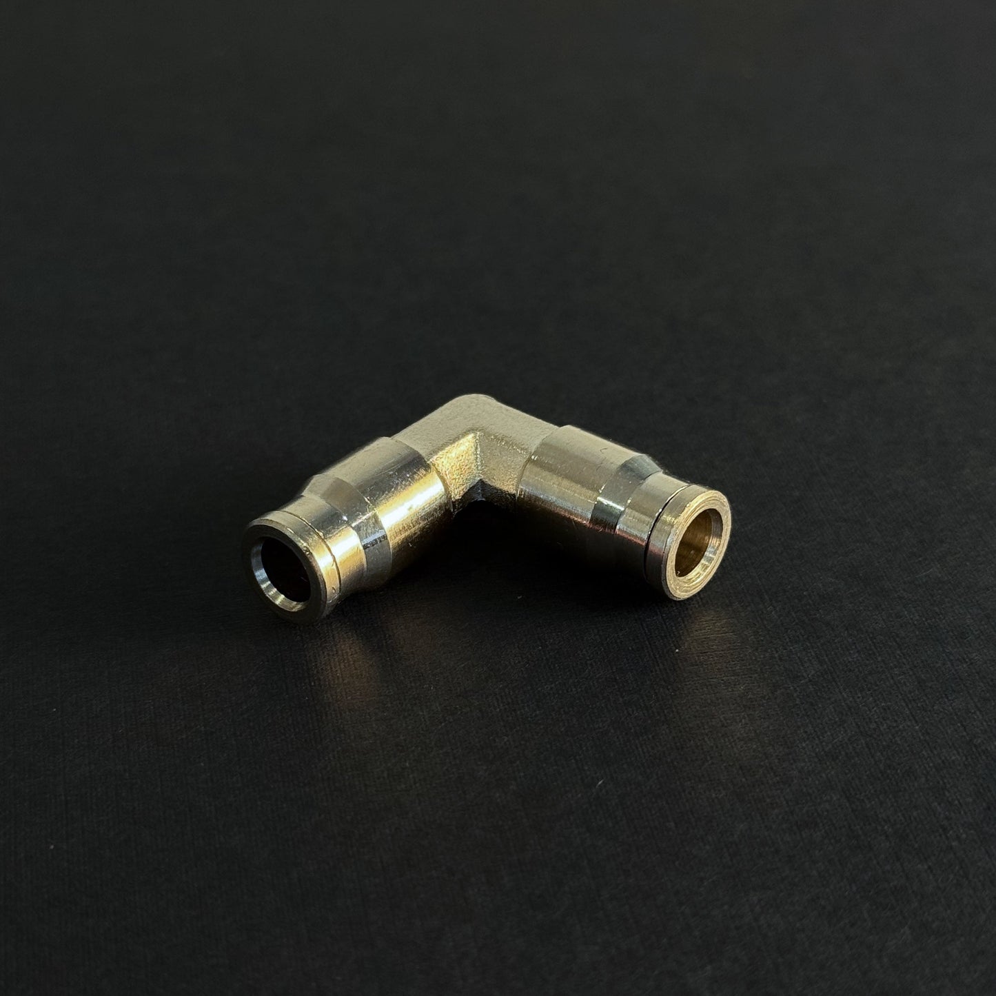 A quick connect elbow fitting for a high pressure misting system on a dark background