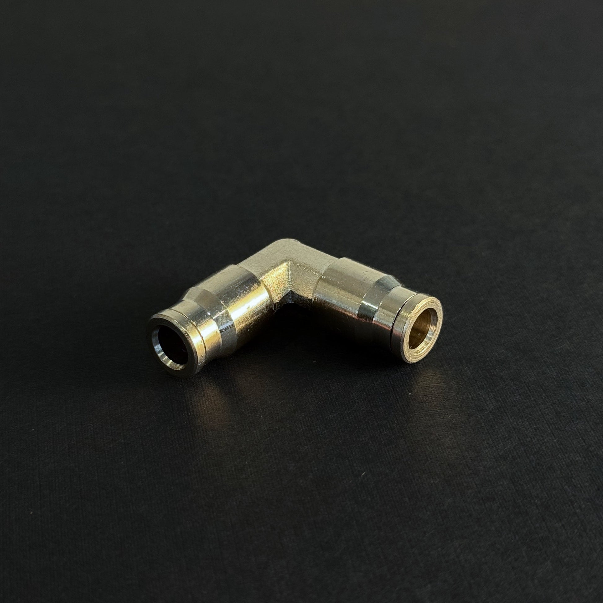 A quick connect elbow fitting for a high pressure misting system on a dark background