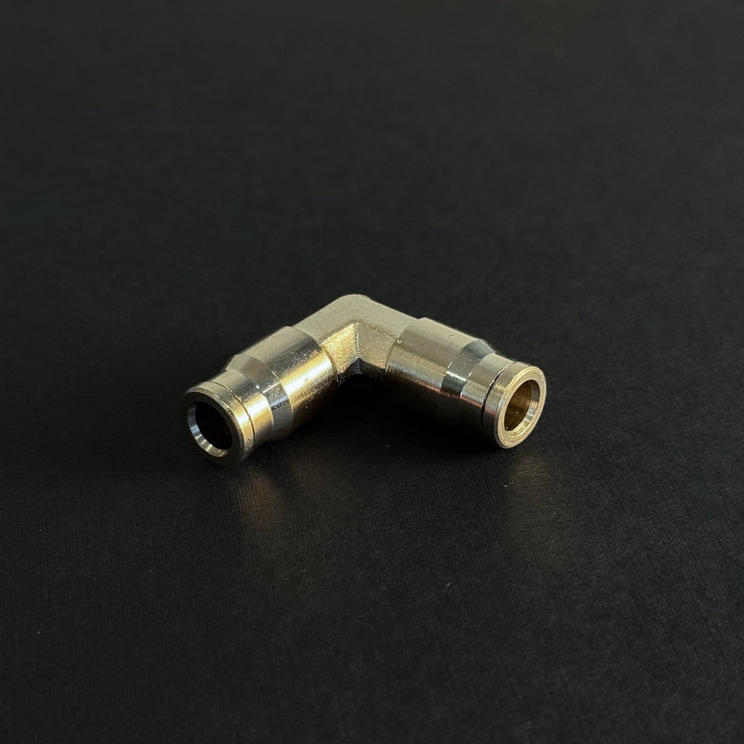 A quick connect elbow fitting for a high pressure misting system on a dark background
