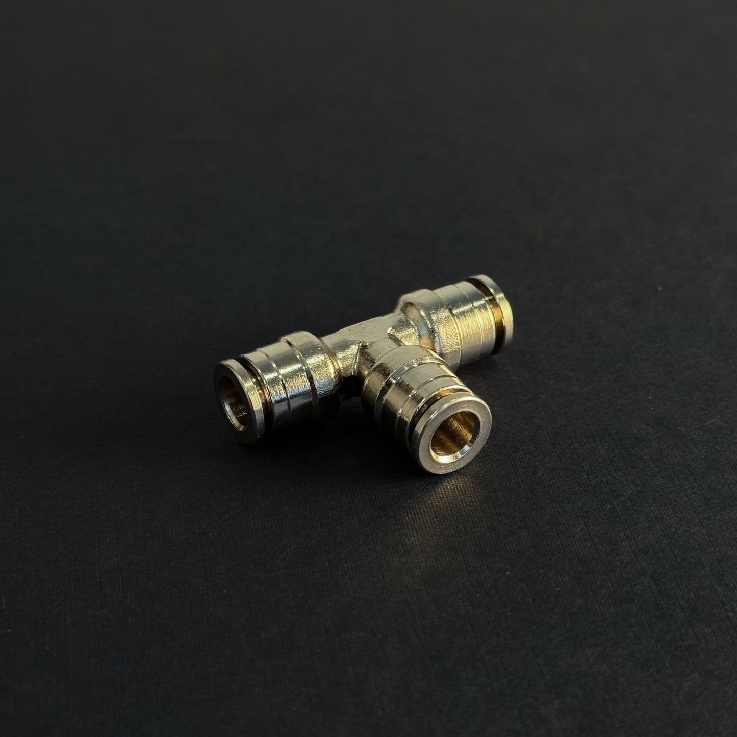 A quick connect tee type fitting for high pressure misting systems on a dark background