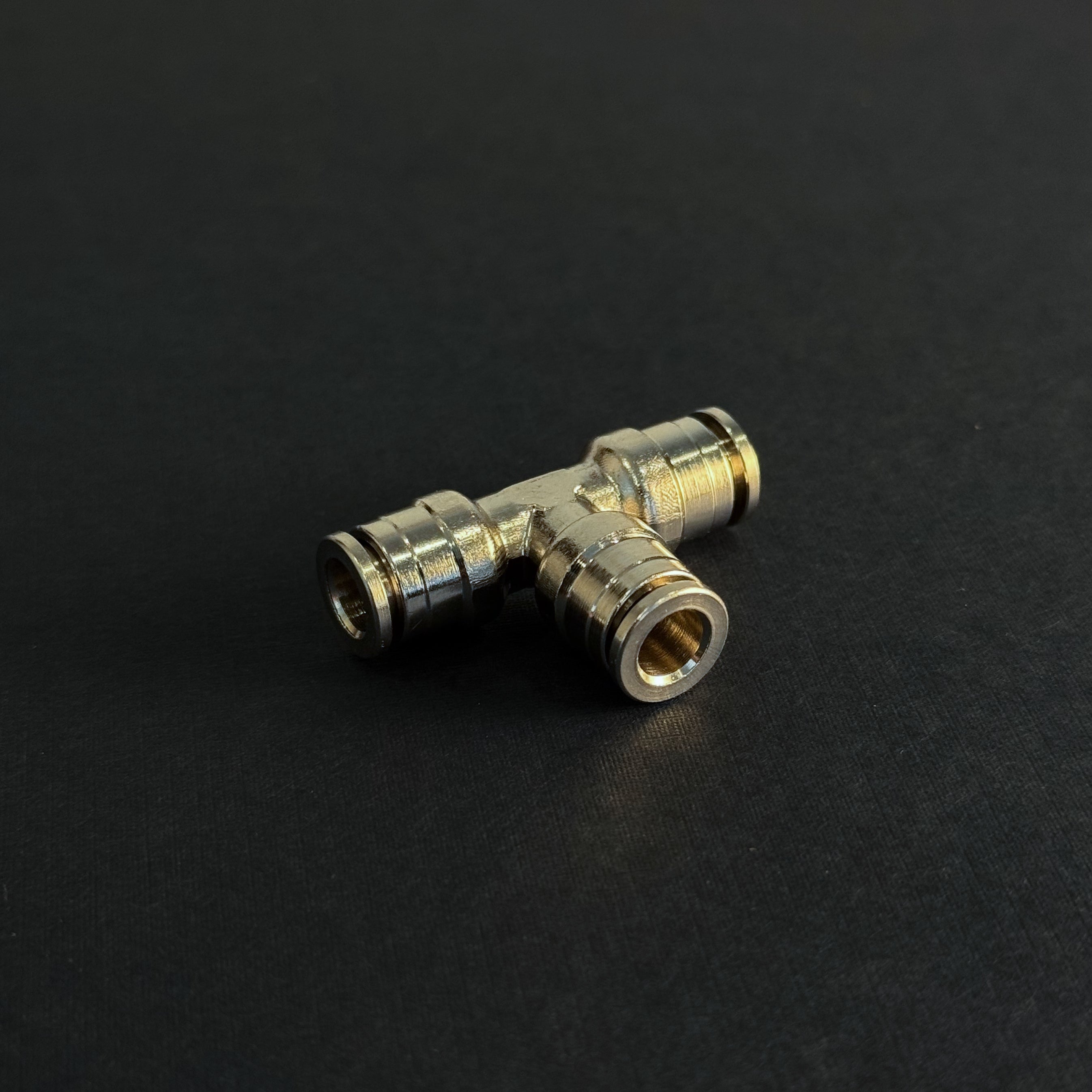 A quick connect tee type fitting for high pressure misting systems on a dark background